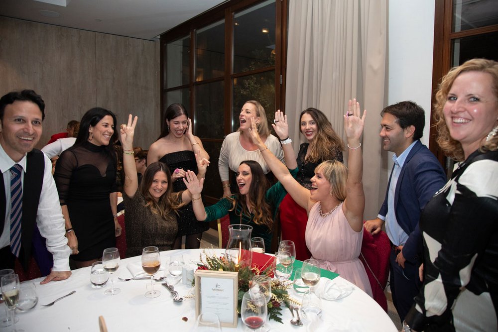 Mitarbeiter aus verschiedenen Abteilungen freuen sich, dass sie das schnellste Team bei Spiel "Stadt, Land, Fluss" waren. Drei Buchhalterinnen reißen die Arme nach oben