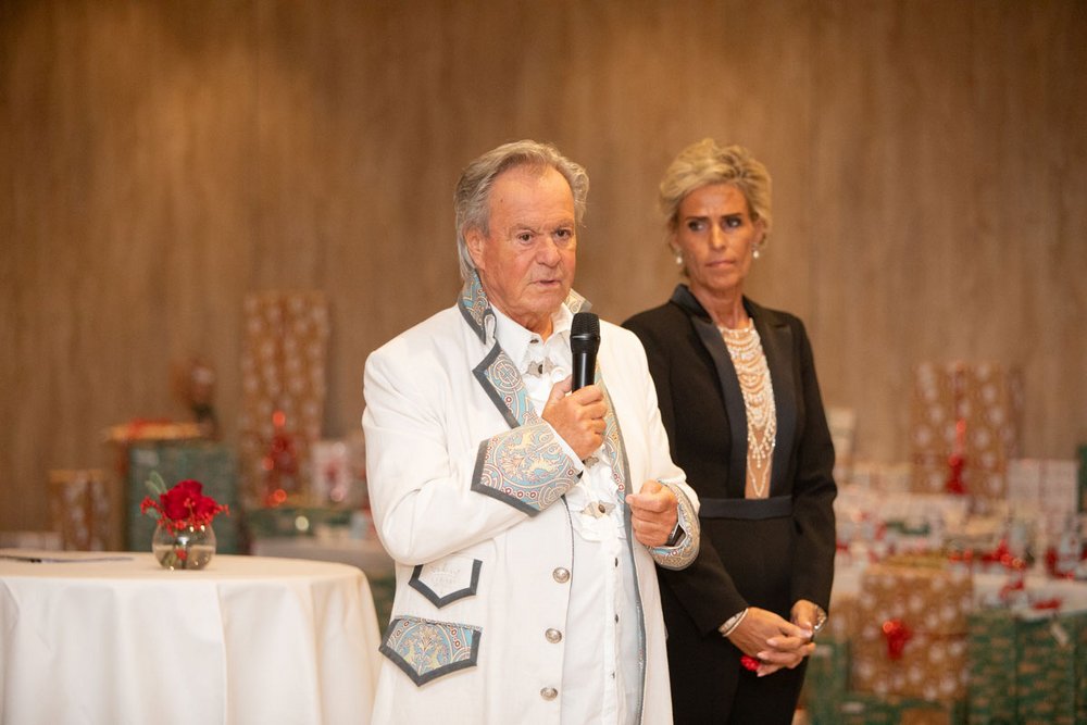 Die Geschäftsführer der PlattesGroup Willi und Yvonne stehen in festlicher Kleidung auf der Weihnachtsfeier. Willi Plattes hält ein Mikrophon in der Hand und hält seine Weihnachtsrede.