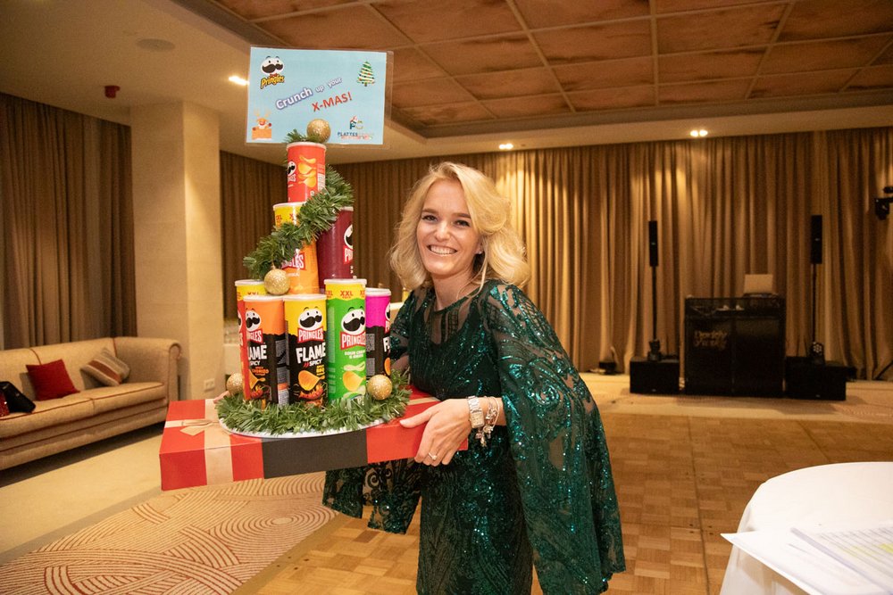 Annika Plattes, Eventmanagerin der PlattesGroup, hält ihr Weihnachtsgeschenk in der Hand. Von den Kollegen hat sie einen Pringles-Adventskalender geschenkt bekommen, die Chipspackungen stapeln sich zu einem hohen Turm auf