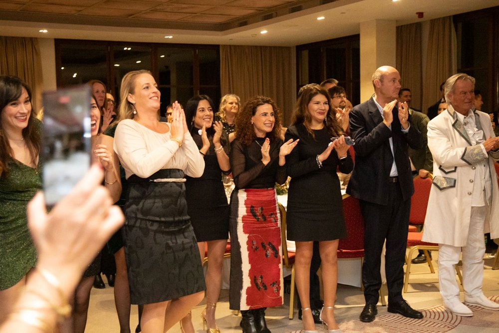 Mitarbeiter der PlattesGroup in festlicher Kleidung lachen und klatschen auf der Weihnachtsfeier des Unternehmens